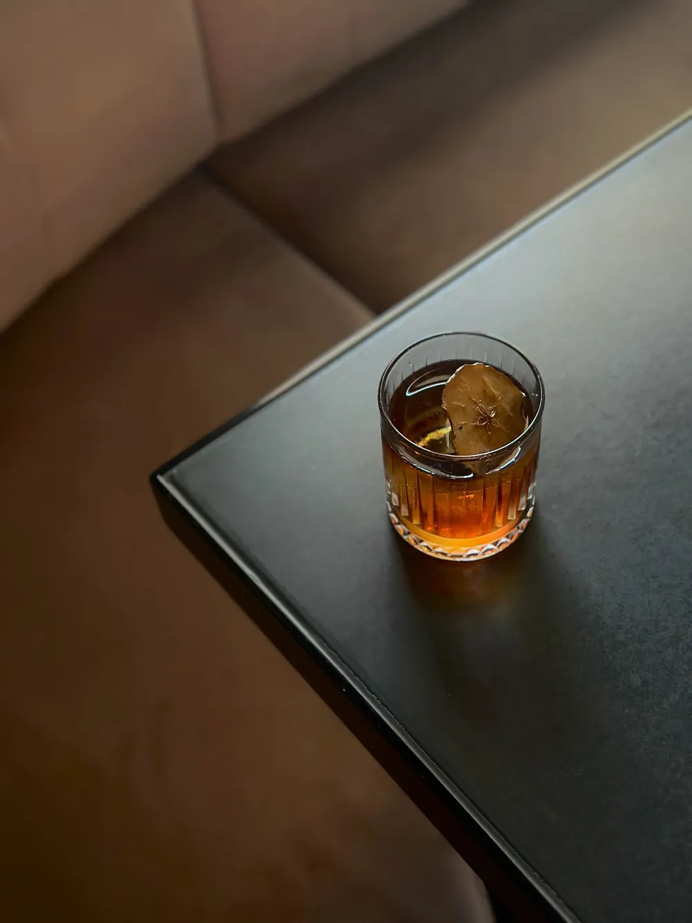 A glass of iced tea with a lemon wedge on a black table.